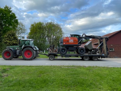 Grüner Traktor zieht einen Anhänger mit landwirtschaftlicher Maschine und Generator.